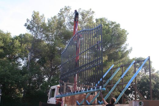 Portail métal soulevé par grue, ciel bleu ; expert CRC Antibes, traitement et livraison régionale.