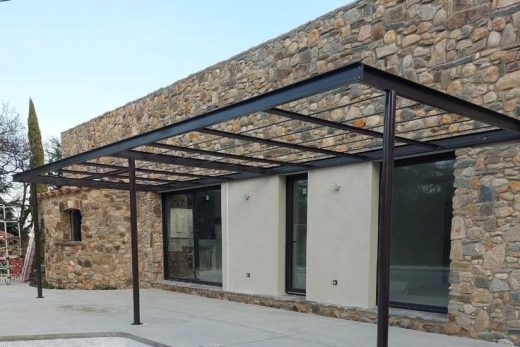 Atelier familial à Antibes avec pergola métallisée, vitrages modernes et piscine vidée sur terrasse béton.