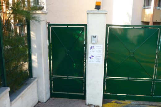 Portail vert métallisé CRC à interphone, notices, sur trottoir marqué jaune à Antibes.